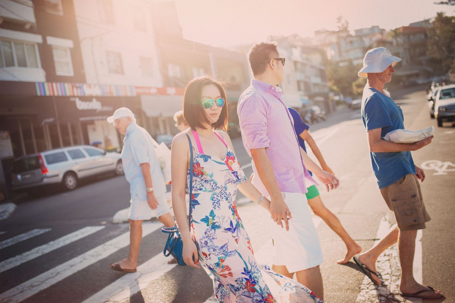 Couple walking across sunny street crossing in colorful summer outfits with golden backlight.
