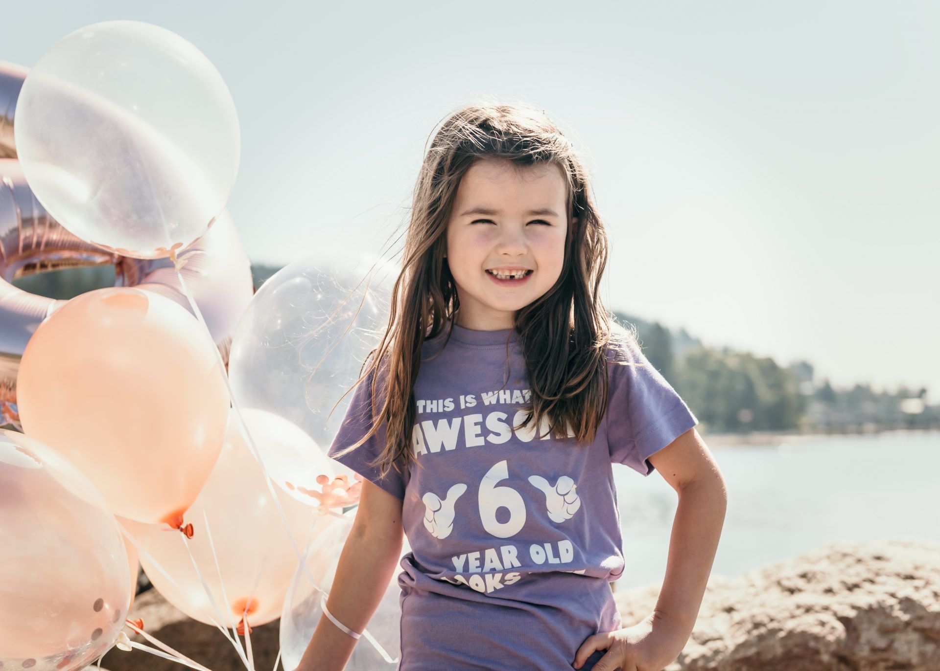 Summer portrait with pastel balloons against a bright mountain landscape.