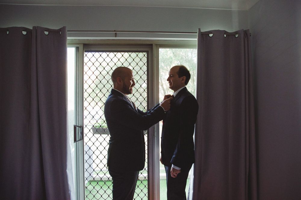 Silhouettes of people getting ready by a window with dark curtains.
