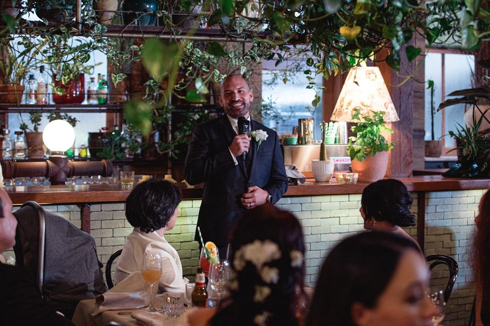 Wedding reception guests enjoying a lively indoor celebration with warm lighting and rustic decor.