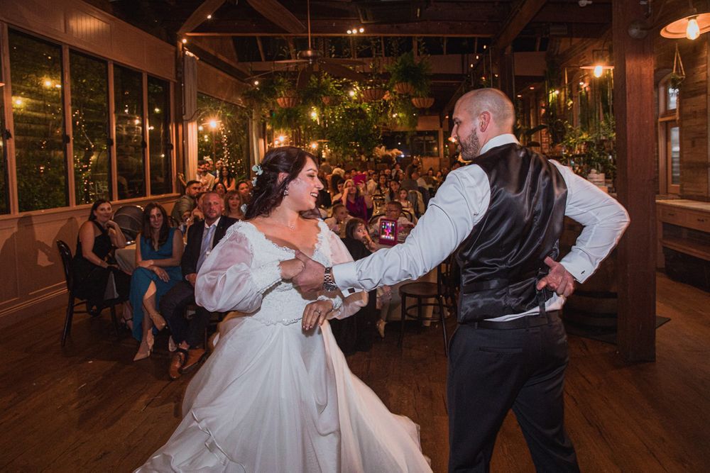 Couple sharing their first dance on a wooden floor during an intimate indoor wedding reception.