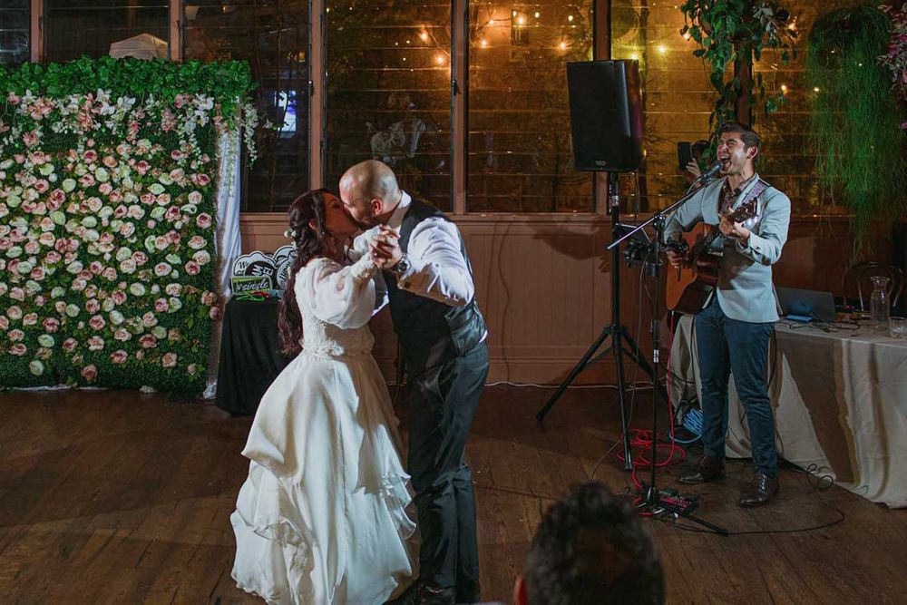 Wedding dance celebration in a rustic venue with romantic lighting and floral decorations.