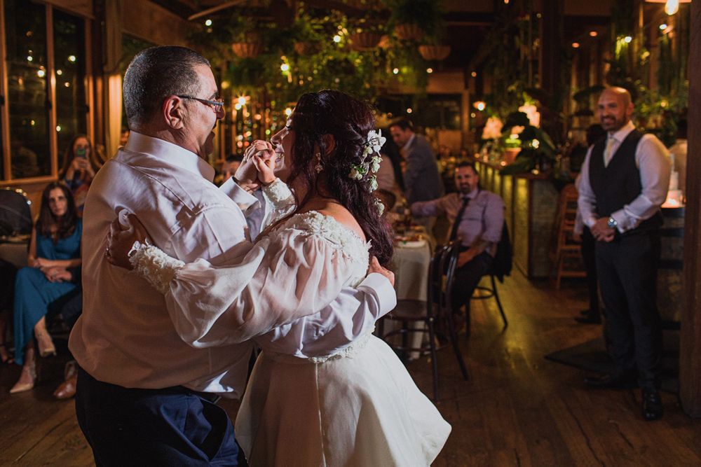 Wedding dance celebration with guests watching in a rustic indoor venue with ambient lighting.