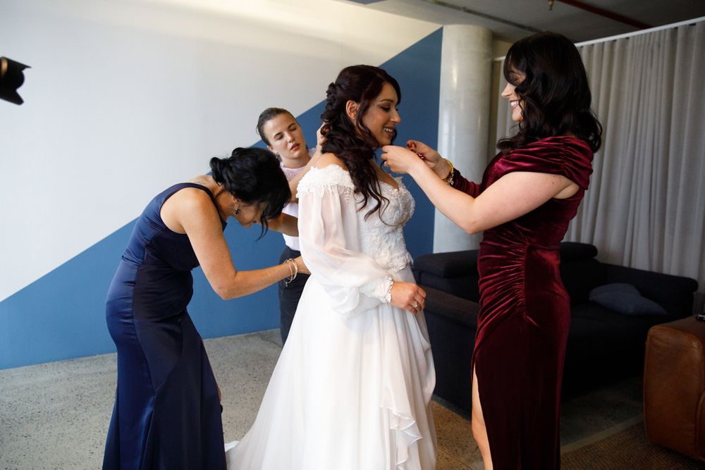 Wedding party members sharing joyful moments in burgundy and white dresses.