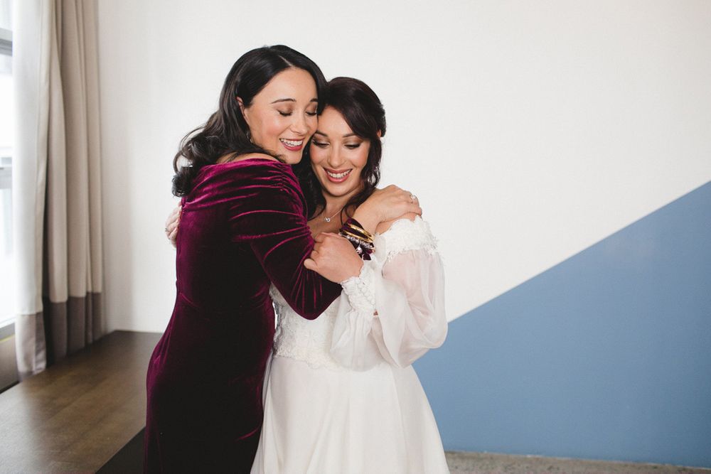 Emotional embraces between wedding party members in white and burgundy dresses.