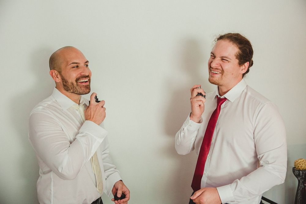 Wedding party members share laughs while getting ready in formal attire.