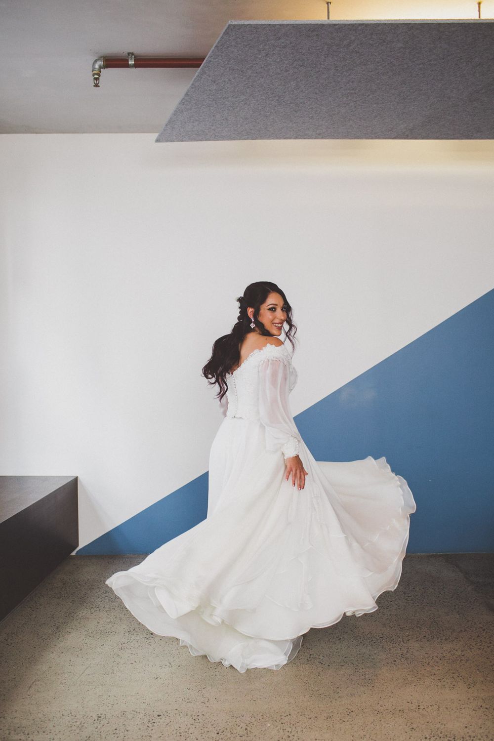 Artistic series of a bride in a flowing white gown creating dynamic poses against a blue and white wall.
