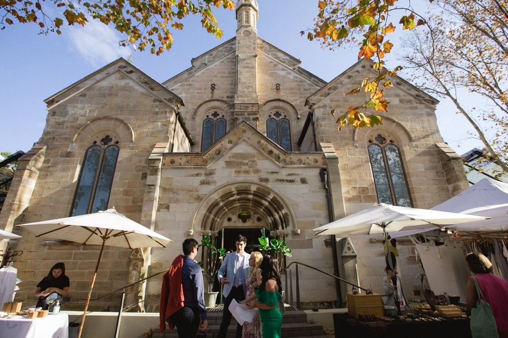 Exterior view of a stone church with Gothic architecture and autumn foliage.