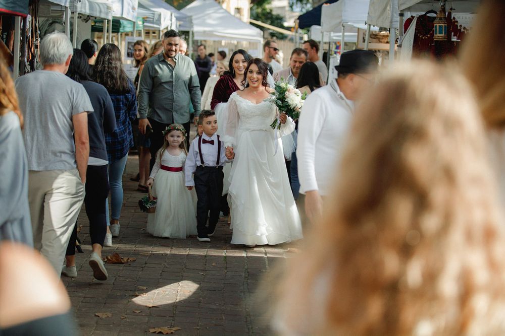 Wedding guests gathered outdoors under blue skies at a celebration.