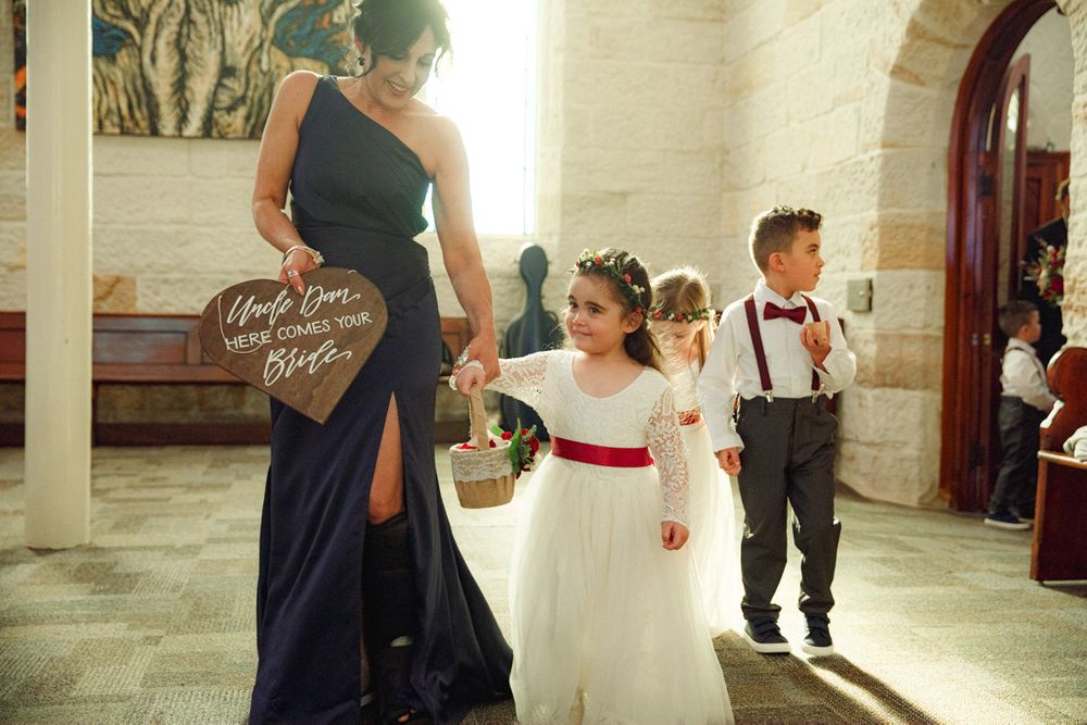Wedding party members walking through a stone church interior with bright natural lighting.