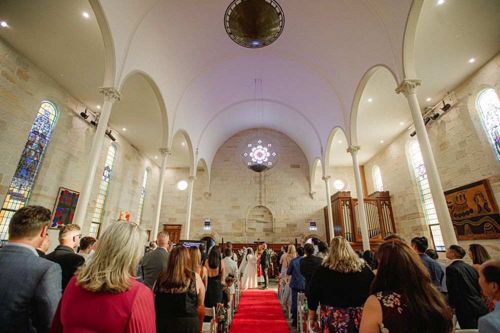 A beautiful church interior with vaulted ceilings and stained glass windows during a wedding ceremony.