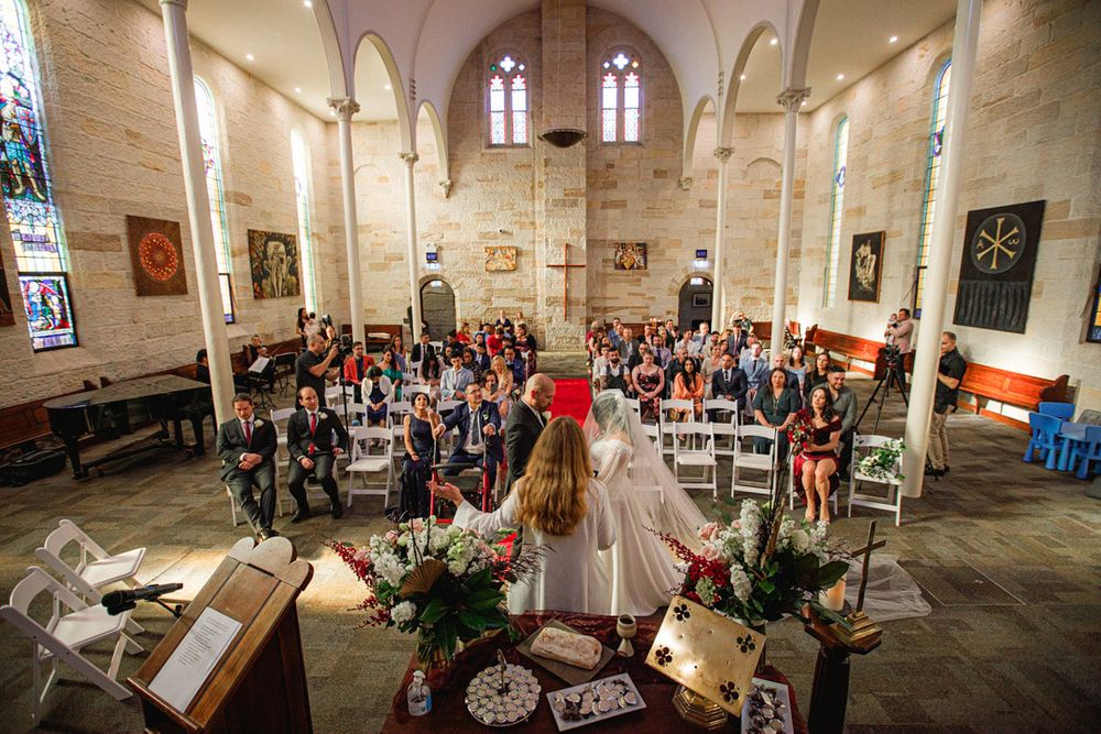 Wide angle view of a church sanctuary with wooden pews and elegant architectural details.
