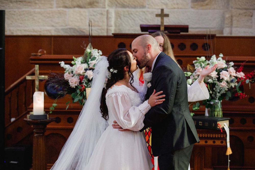 Romantic wedding moment captured in a historic church sanctuary with stone walls.