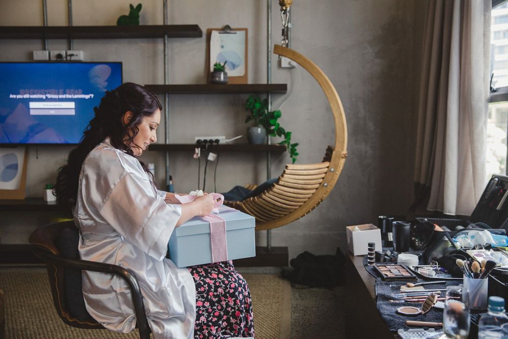 Bridal preparations take place in a modern room with hanging chair and natural lighting.