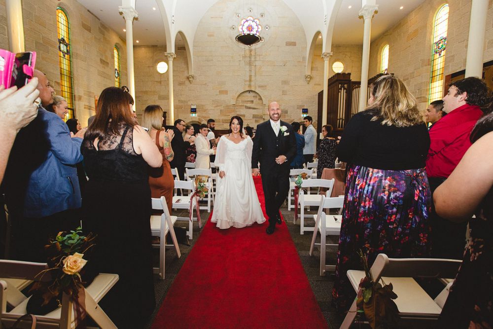Wedding guests celebrate during an indoor reception with festive lighting and decor.