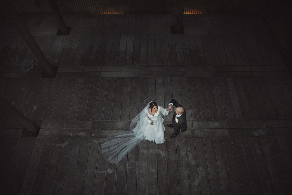 Dark moody wedding portrait in dimly lit historic brick passageway.
