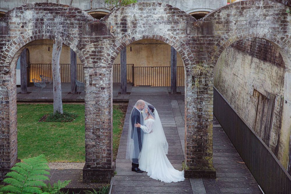 Elegant wedding photography session in historic brick archway setting.