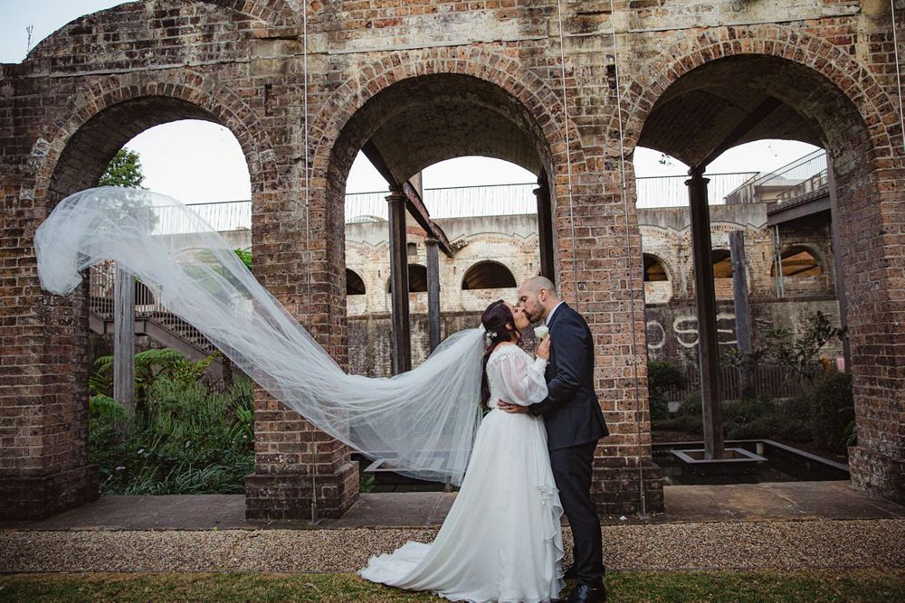 A romantic wedding moment captured under historic brick archways.