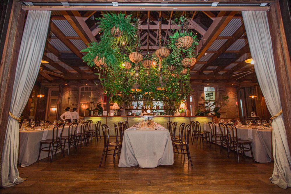Panoramic view of an elegant wedding reception hall with draped fabric and greenery.