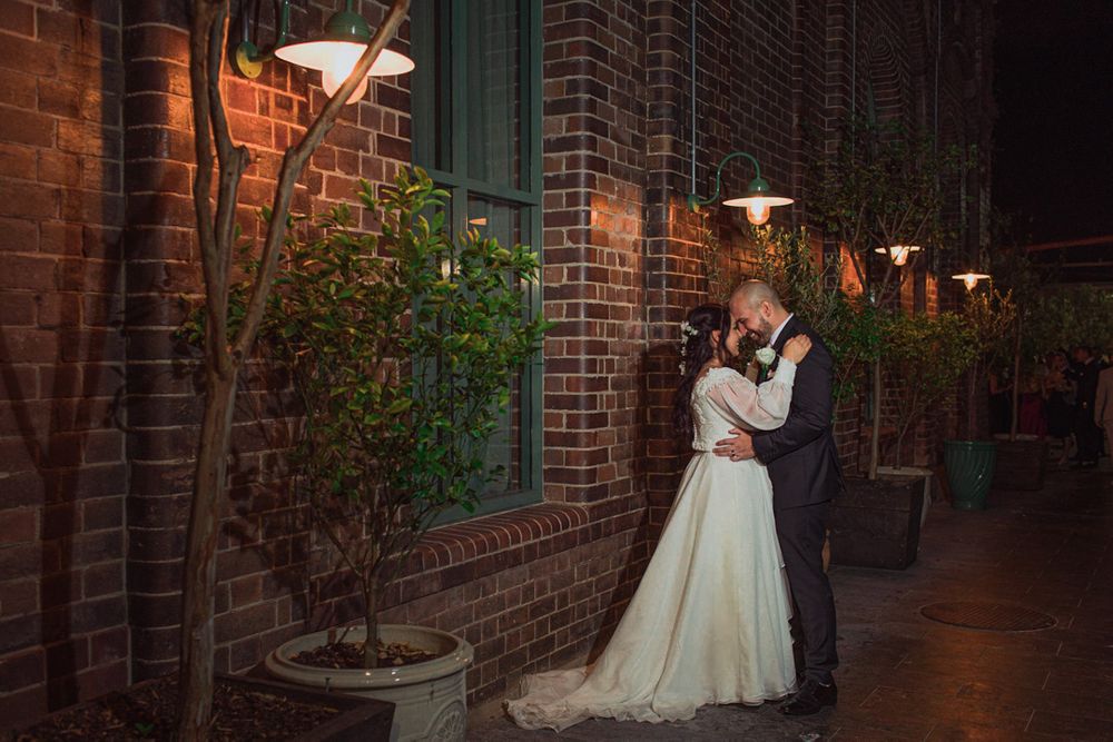 Evening wedding photos in a brick-lined corridor with atmospheric lighting.