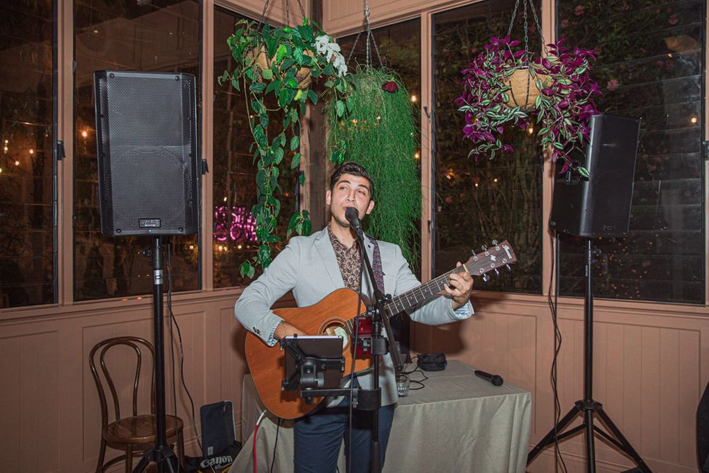 Live acoustic guitarist performing at an intimate indoor venue with mood lighting.