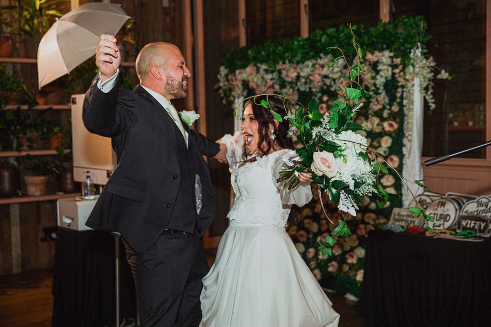 Couple dancing together during their wedding reception surrounded by decorative greenery.