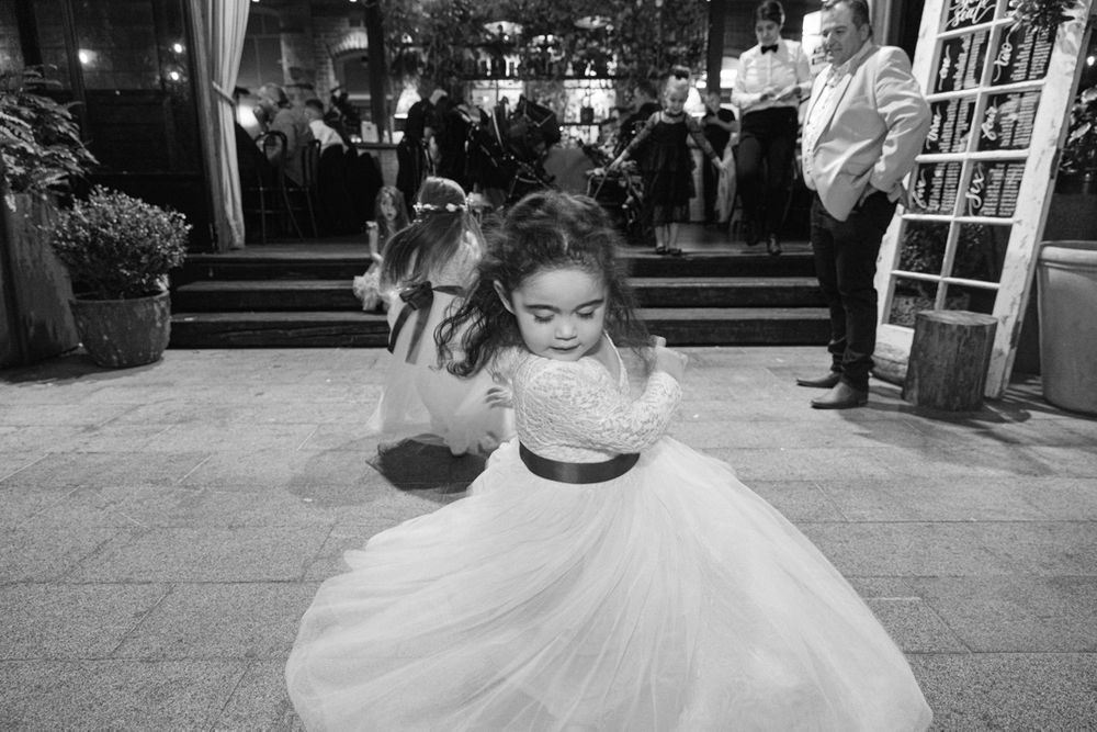 Wedding celebration with guests dancing on a wooden floor under ambient lighting.