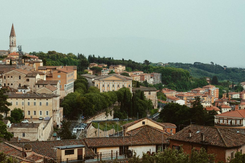 Aerial view of a charming Italian hillside town with terracotta roofs and church tower.