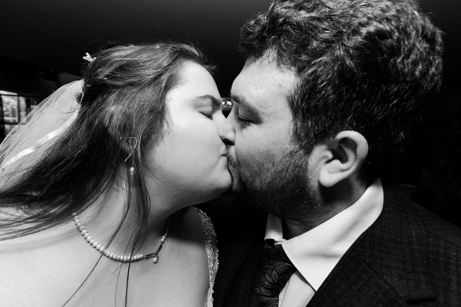 Bride and groom is wedding attire kissing in black and white