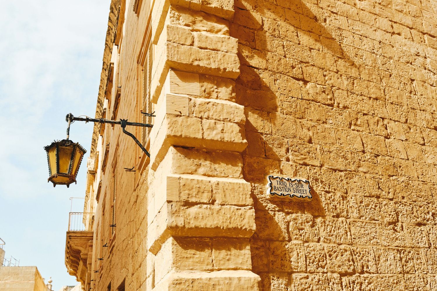 Vintage stone wall with ornate lantern fixture in Mediterranean architecture style.