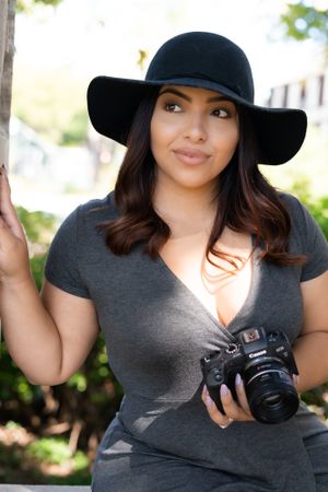 Portrait session with camera and black hat in outdoor setting.