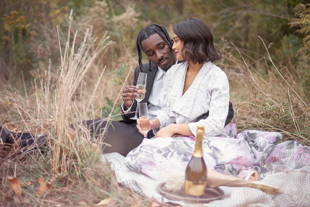 Two friends having a picnic with wine in a rustic outdoor setting.