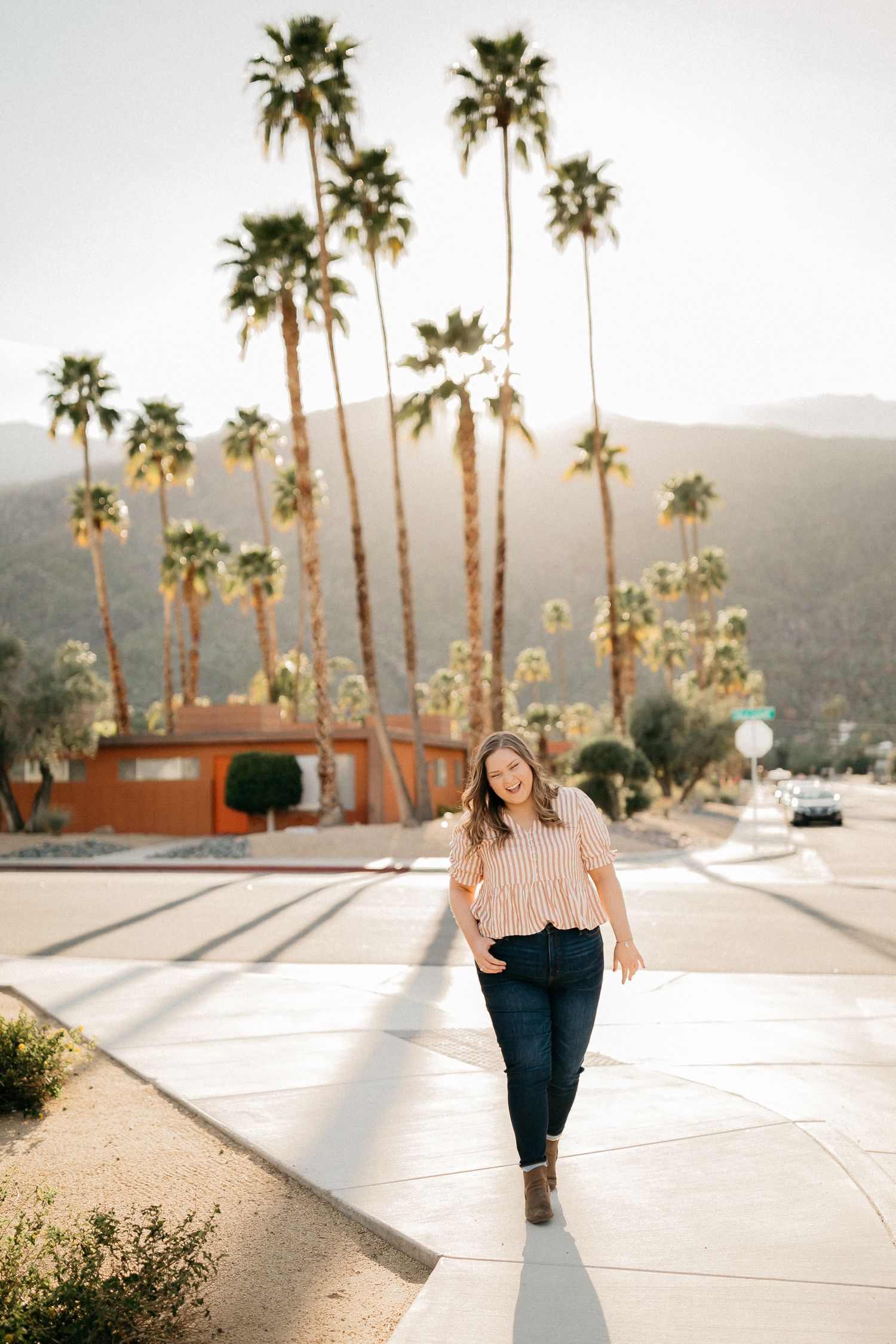 Walking portrait on white pathway with tall palm trees in background.