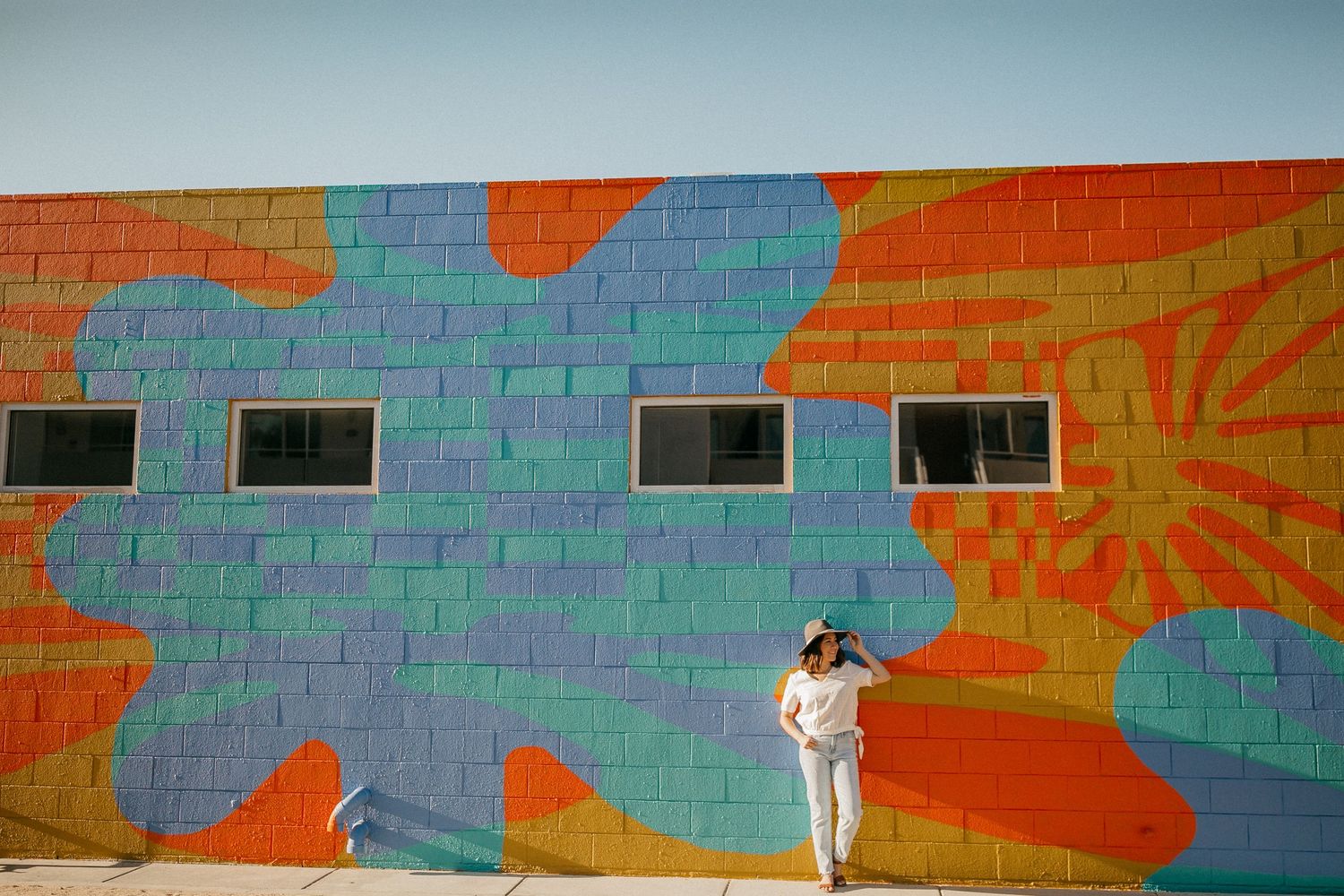Colorful street art mural with blue and orange geometric shapes on brick wall.