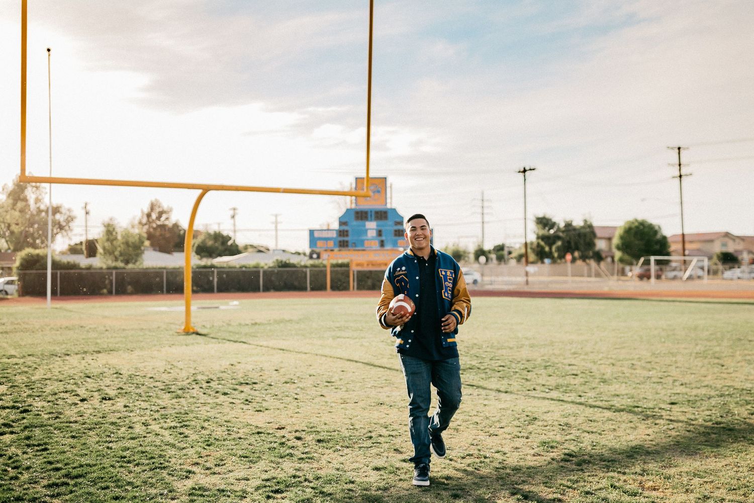 Sports field with goal posts during sunset as athlete runs with camera gear.
