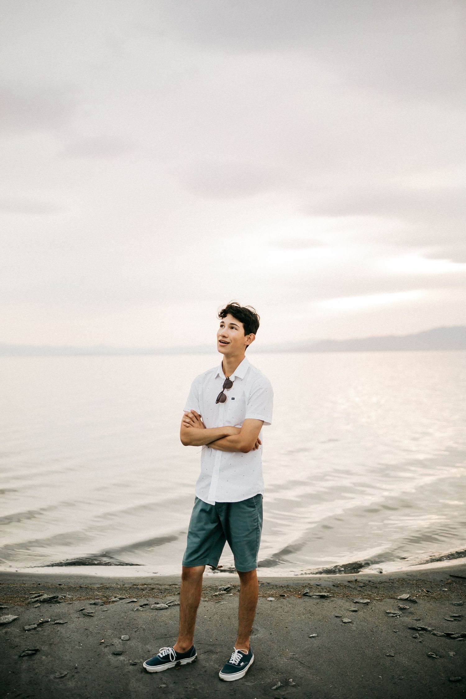 A tranquil scene on a beach with a figure in white shirt and shorts gazing at the misty horizon.