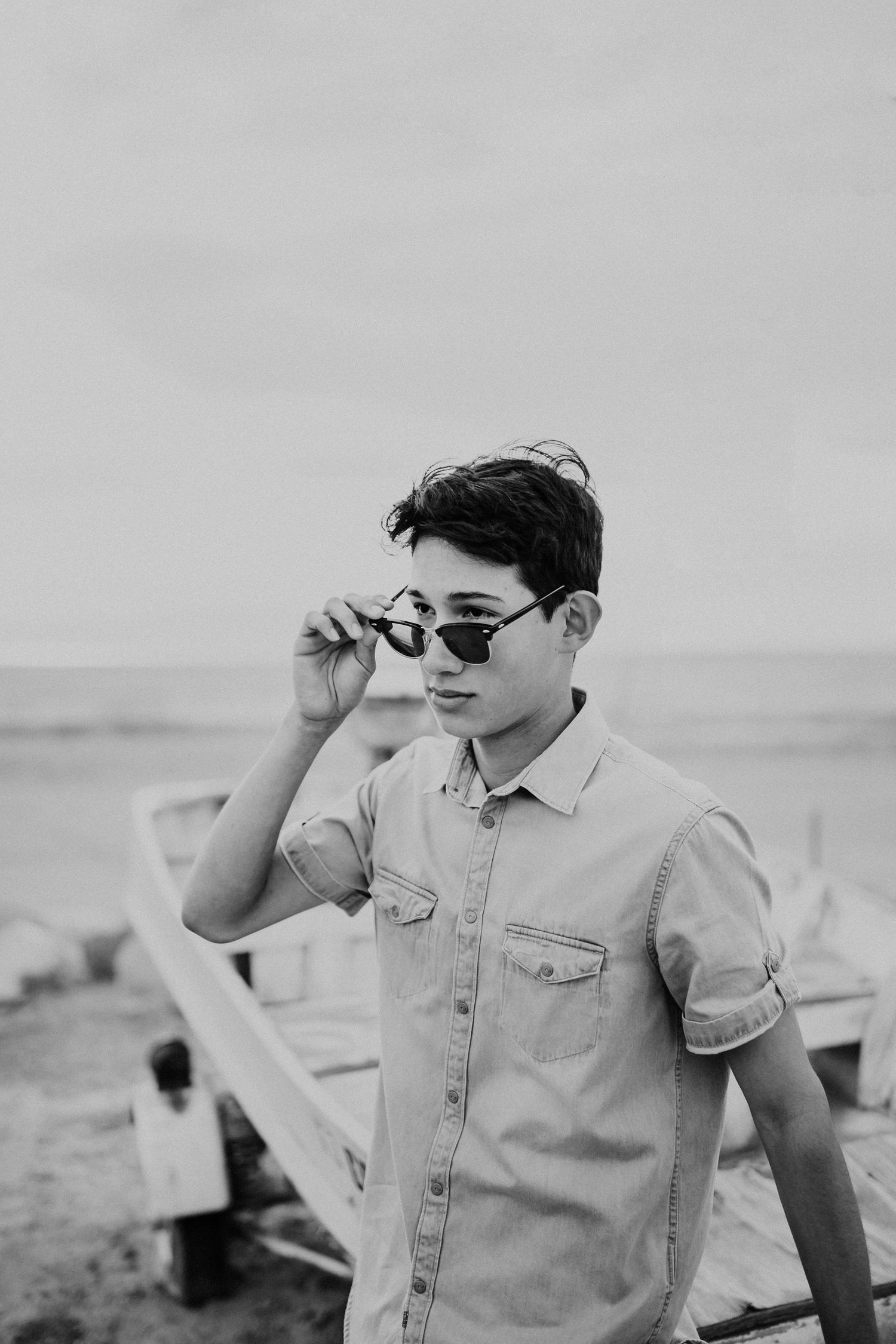 Black and white portrait of casual summer style with sunglasses near beach.