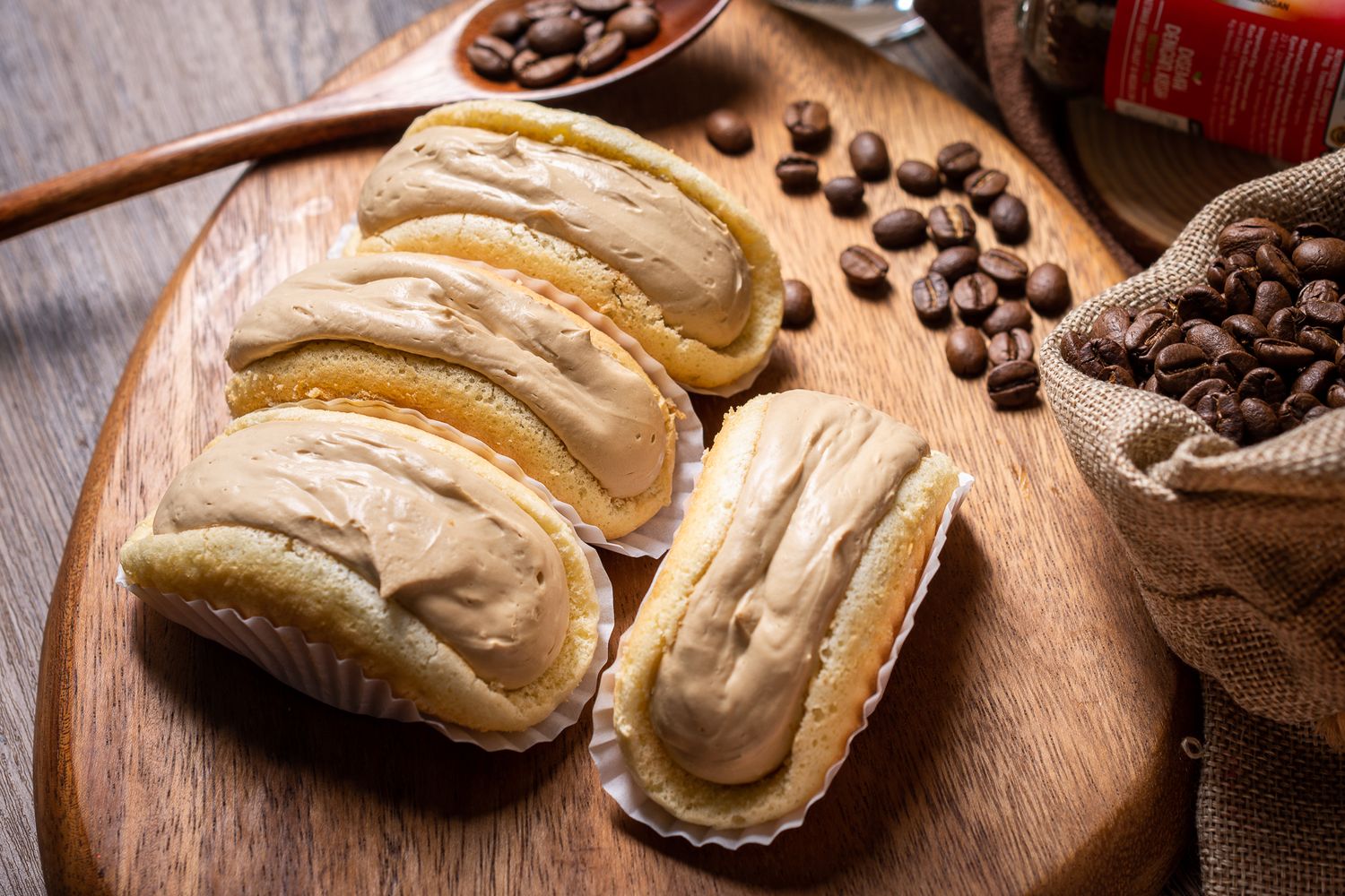 Fresh baked bread rolls with coffee beans scattered on wooden surface.
