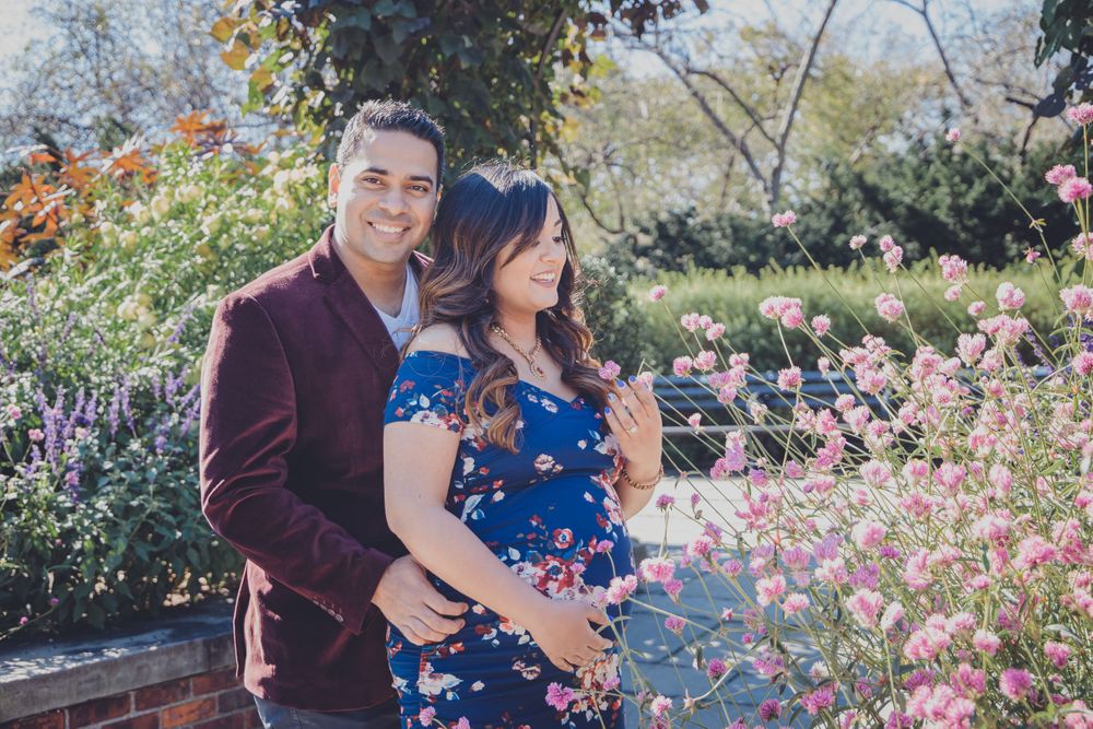 A couple embraces in a garden filled with colorful flowers and blooming plants.
