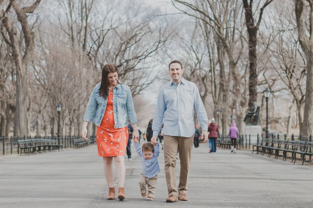 People walking along tree-lined path in Central Park during autumn.