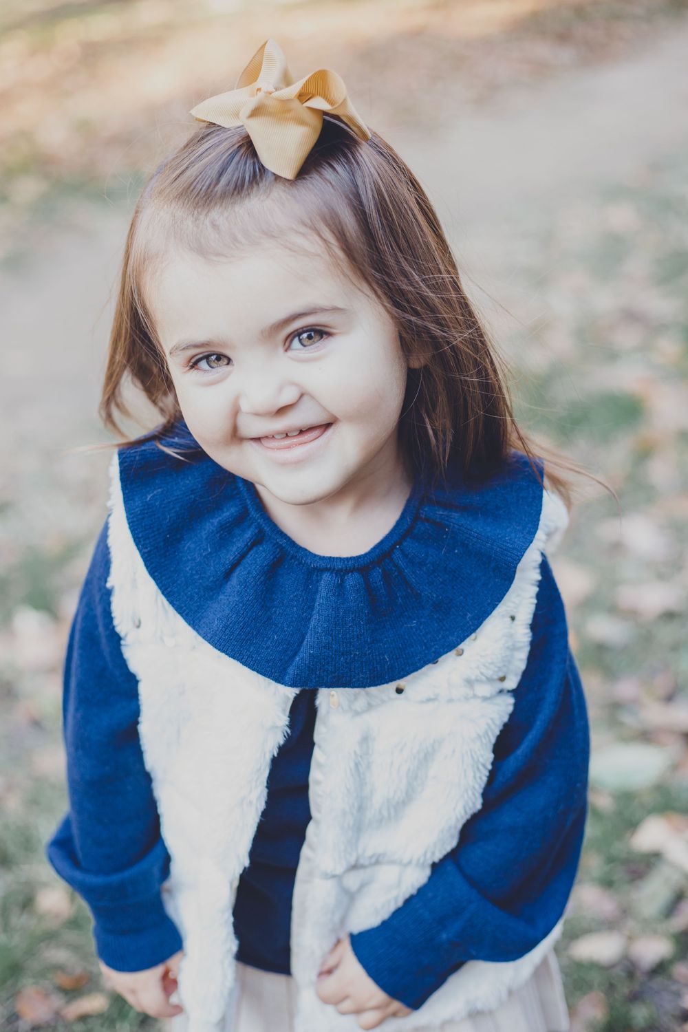 Child wearing a blue and white dress with ruffled collar smiling at camera.