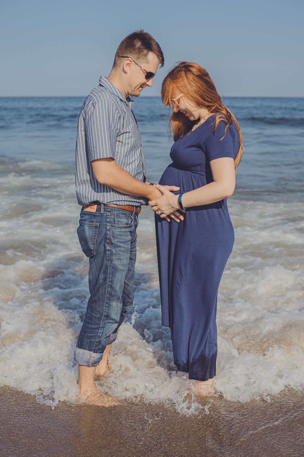 Couple shares tender moments while standing in ocean waves at the beach.