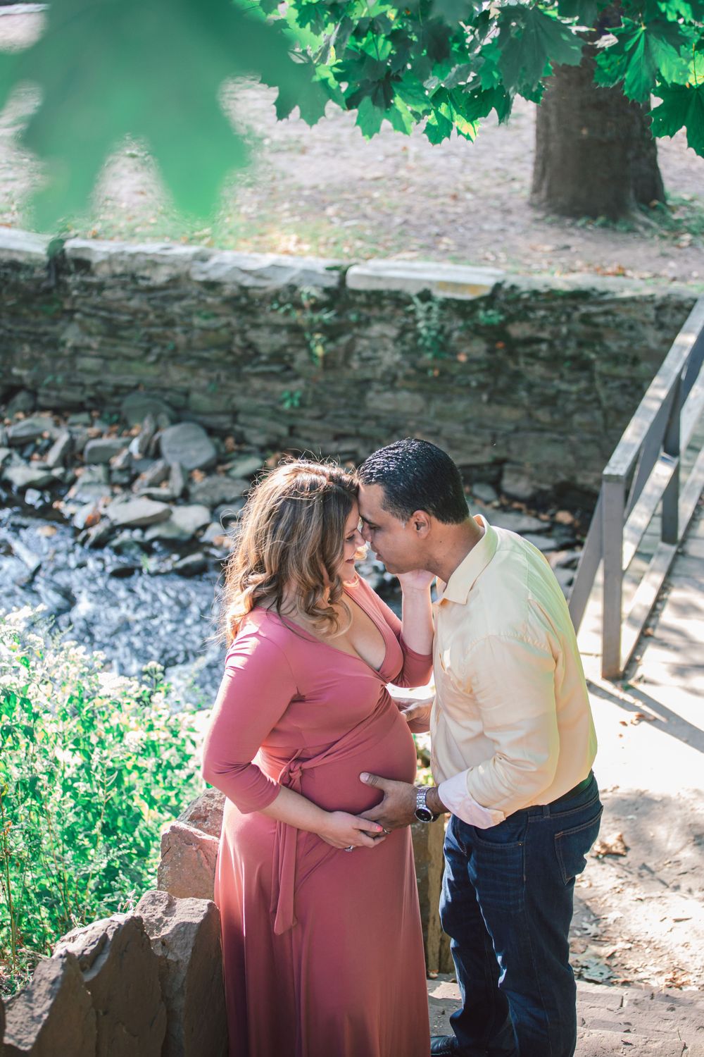 A romantic couple shares intimate moments in a garden setting with a stone wall backdrop.