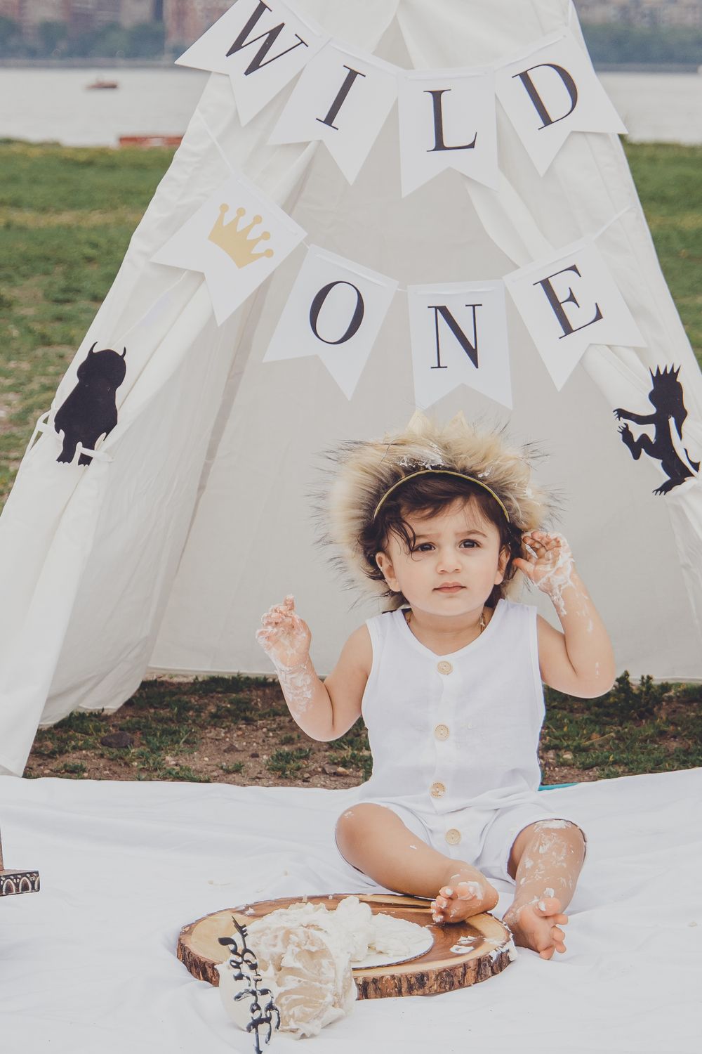 Child plays inside white teepee tent with decorative lettering and animal silhouettes.