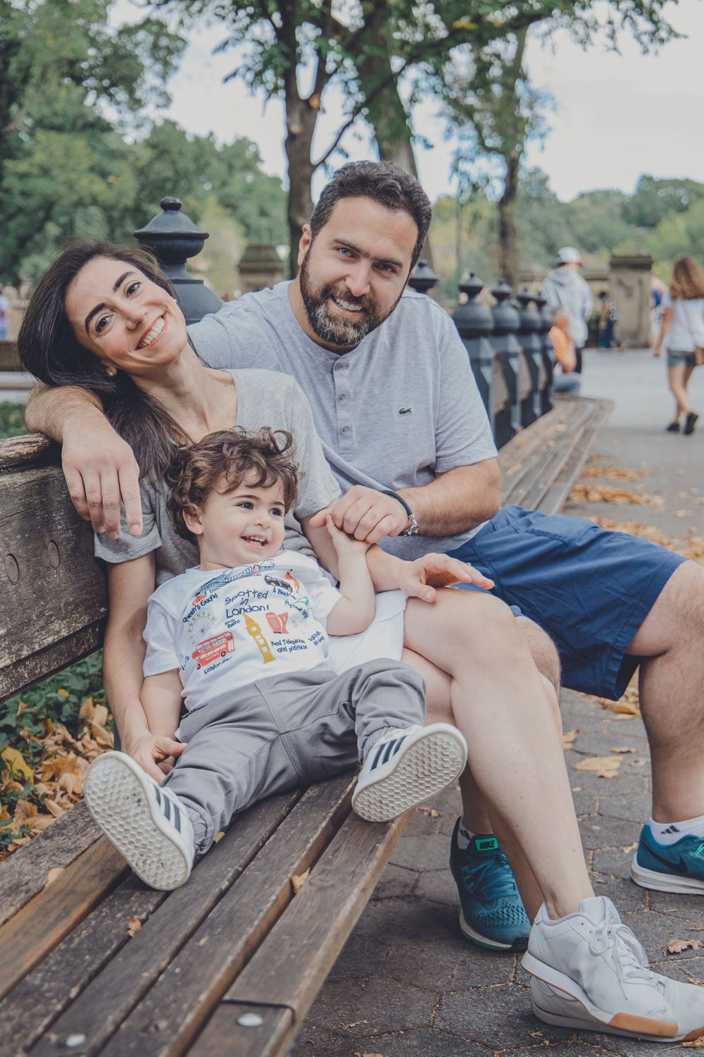 A relaxed family enjoying time together on a park bench near a lake.