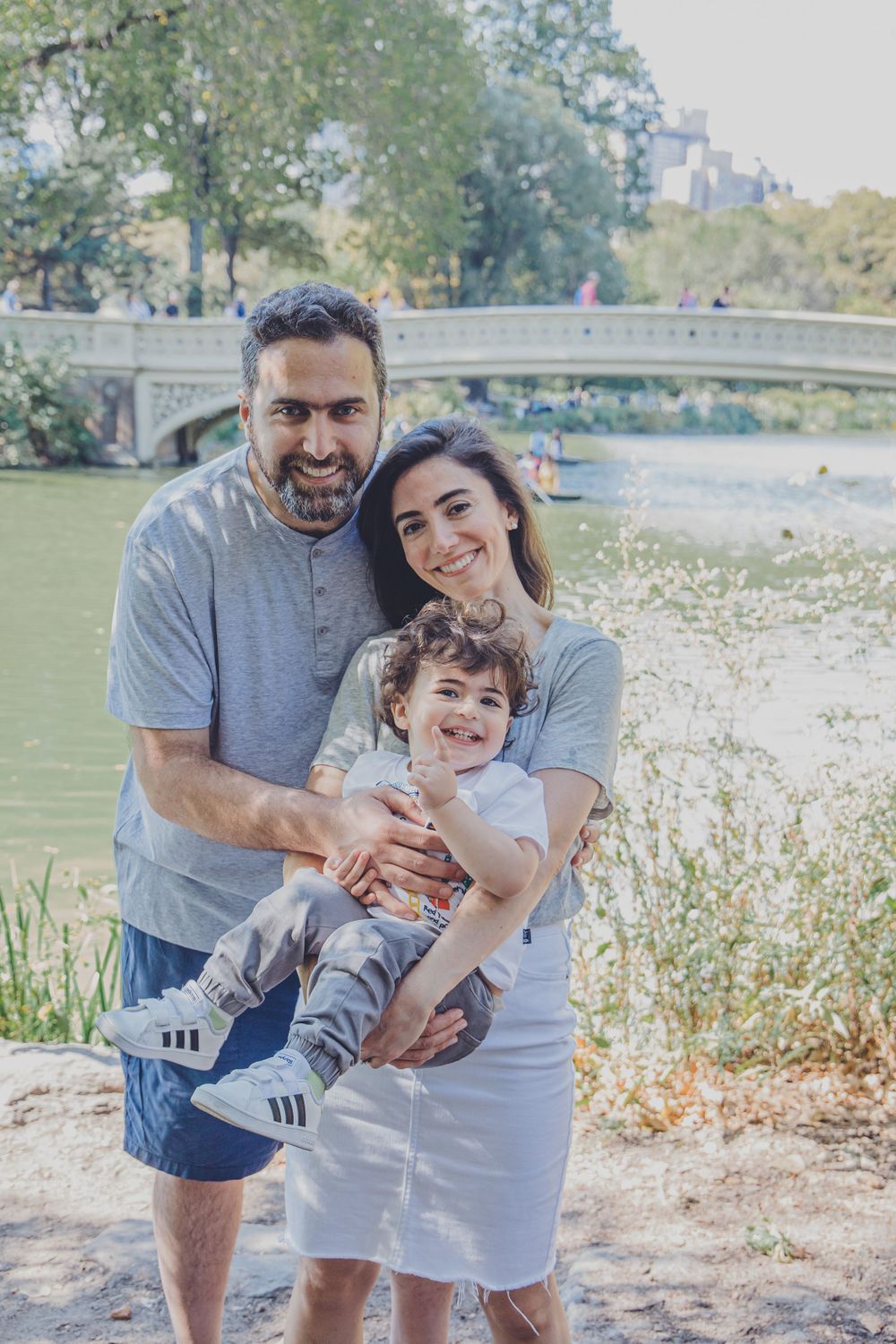 A family shares a joyful moment together by a lake in a park setting.