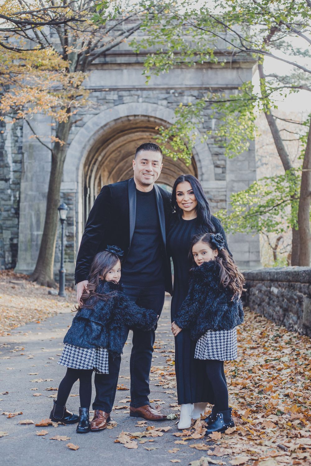 Family portrait session in fall with stone church architecture and scattered leaves.