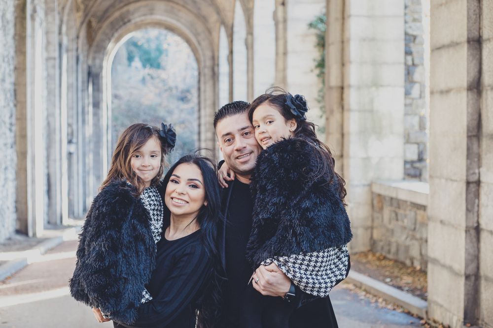 Family photo session by historic stone church columns during autumn.