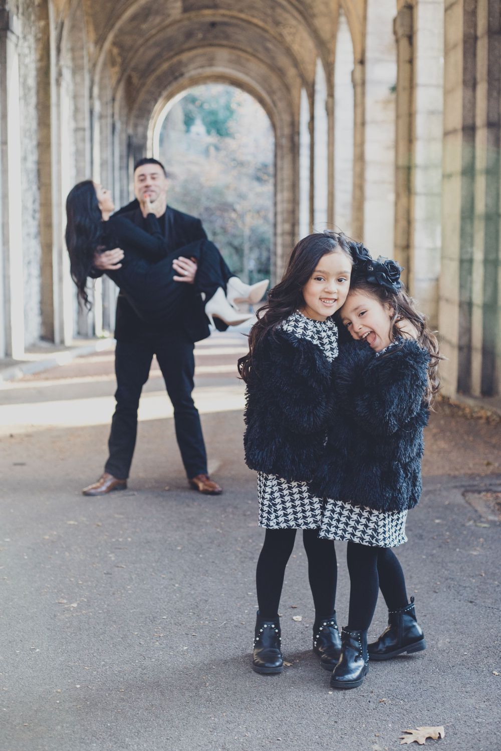 Family photo session showing playful poses in an outdoor stone archway during autumn.