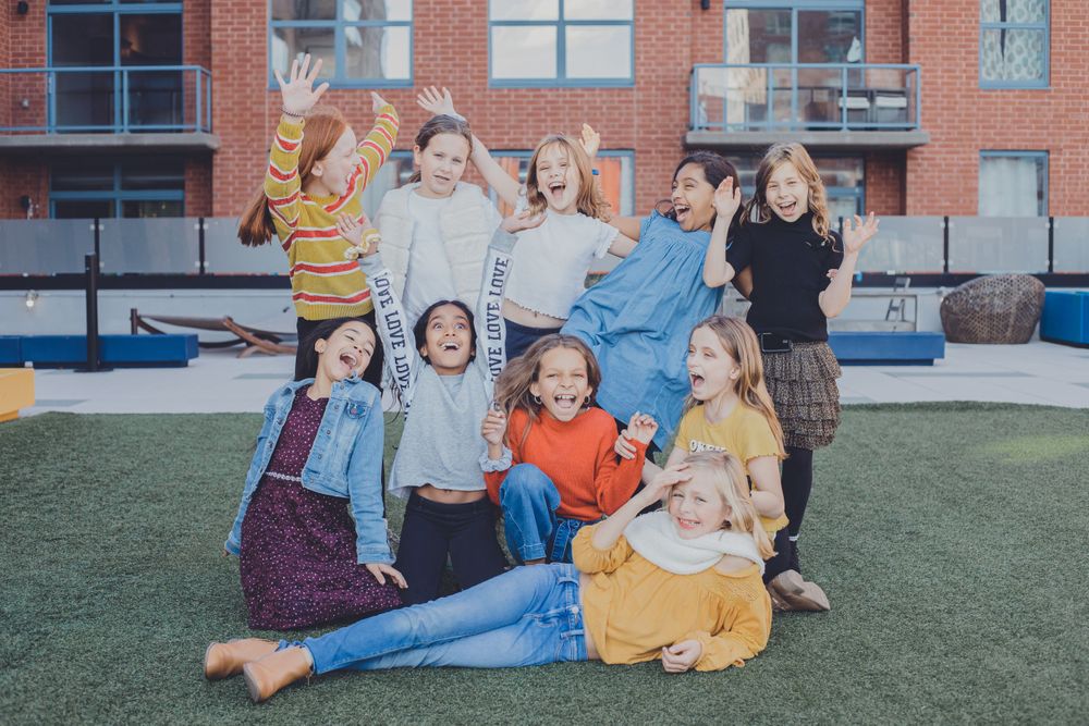 Friends lay in a circle on grass outside a brick building.